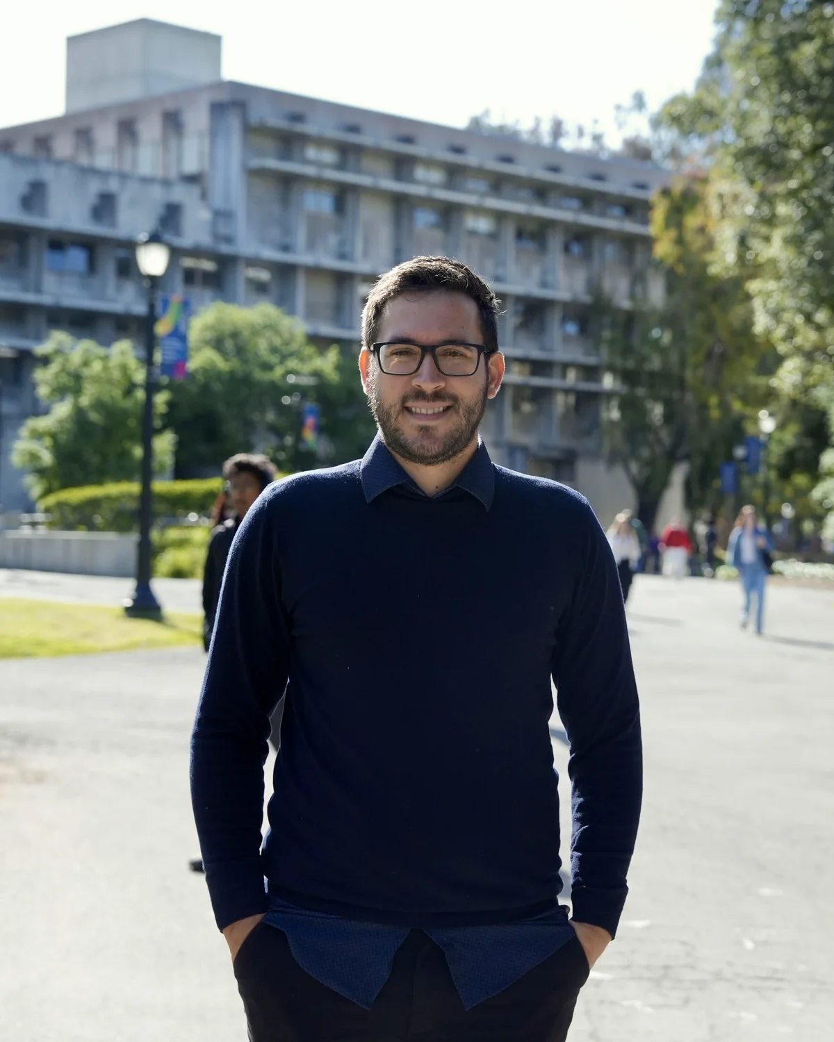José Carlos Amorim em plano de meio corpo no campus da Universidade de Berkeley, olhar direto para a câmera, expressão tranquila.