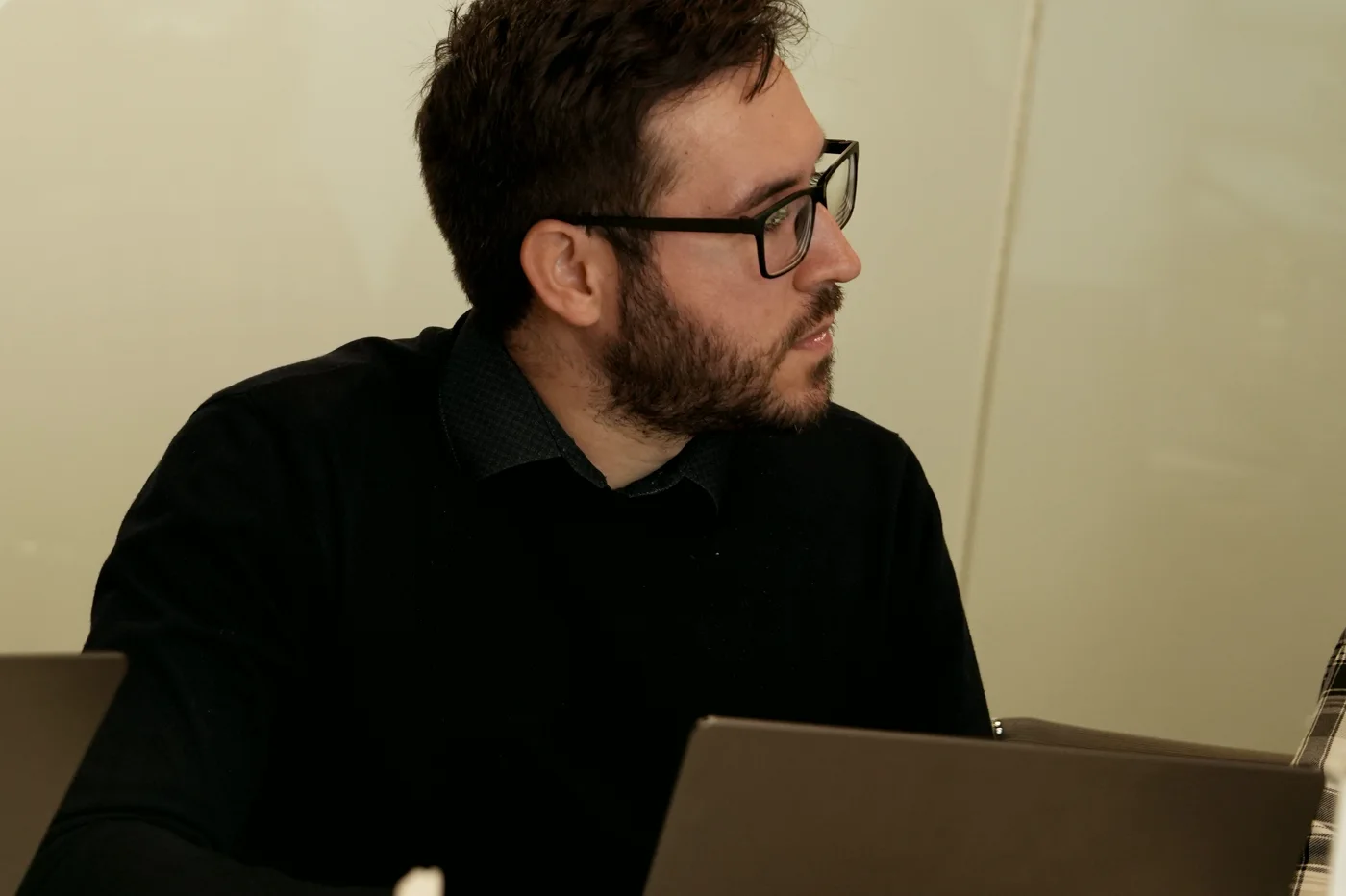 José Carlos Amorim de perfil, vestindo preto, trabalhando em um laptop com luz natural suave.